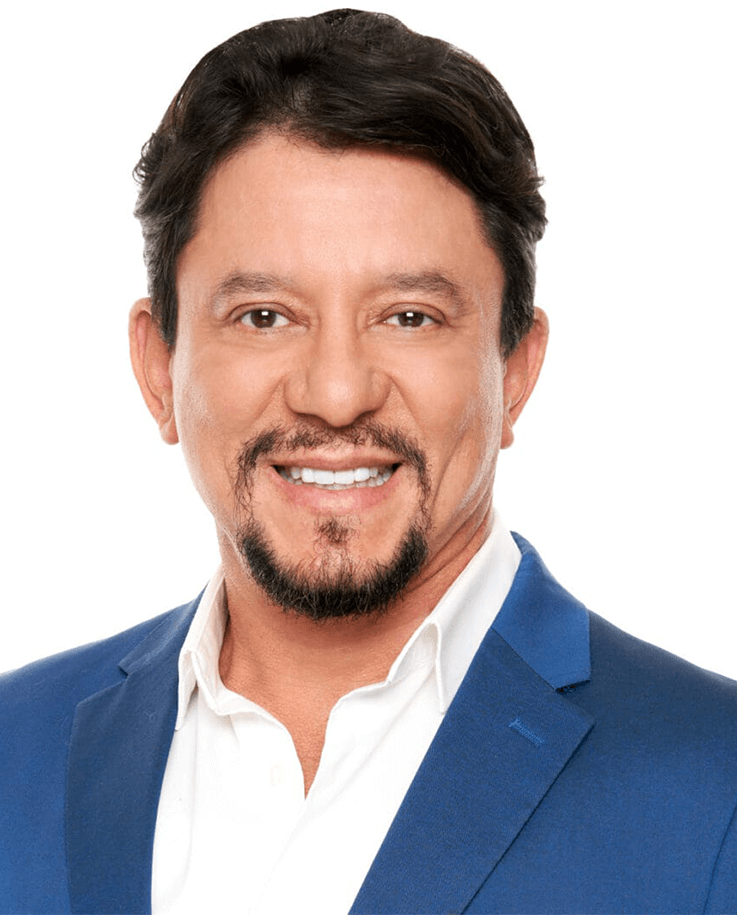 A man with short dark hair and a goatee, wearing a blue suit jacket and white shirt, smiling at the camera against a white background.