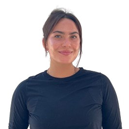 Faith Woman with long dark hair wearing dark scrubs smiles and stands against a plain light background, representing hormone balance at About Dr. Melinda Silva, MD Anti-Aging & Wellness.
